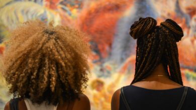 Back of two women's heads, one with textured curly hair and one with box braids.